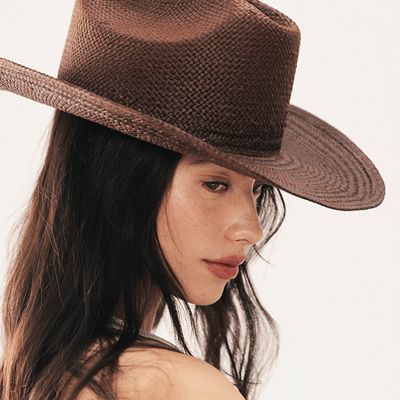 Woman wearing a brown straw hat on a plain background