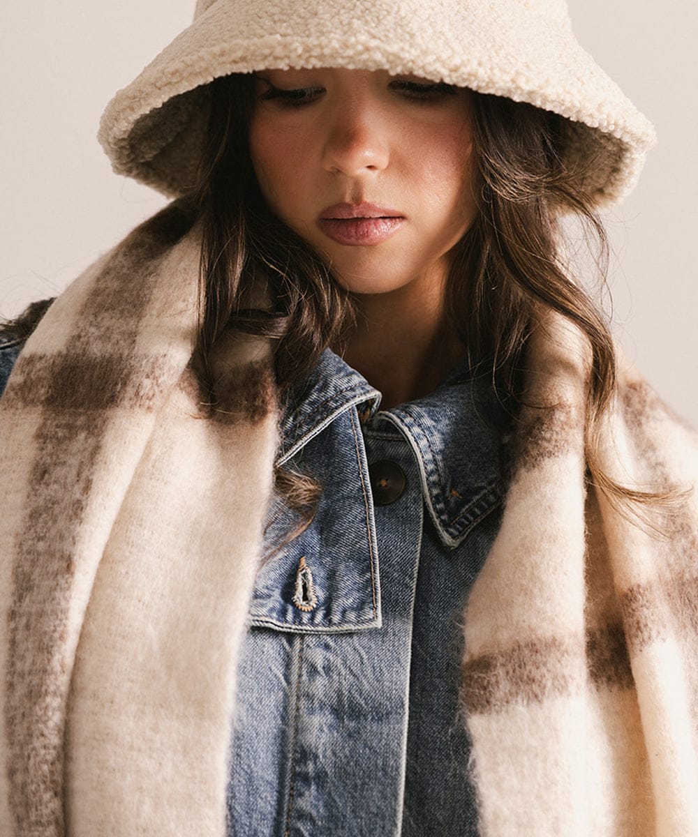 Person wearing a beige hooded coat over a denim jacket with a neutral background #color_ cream - brown plaid