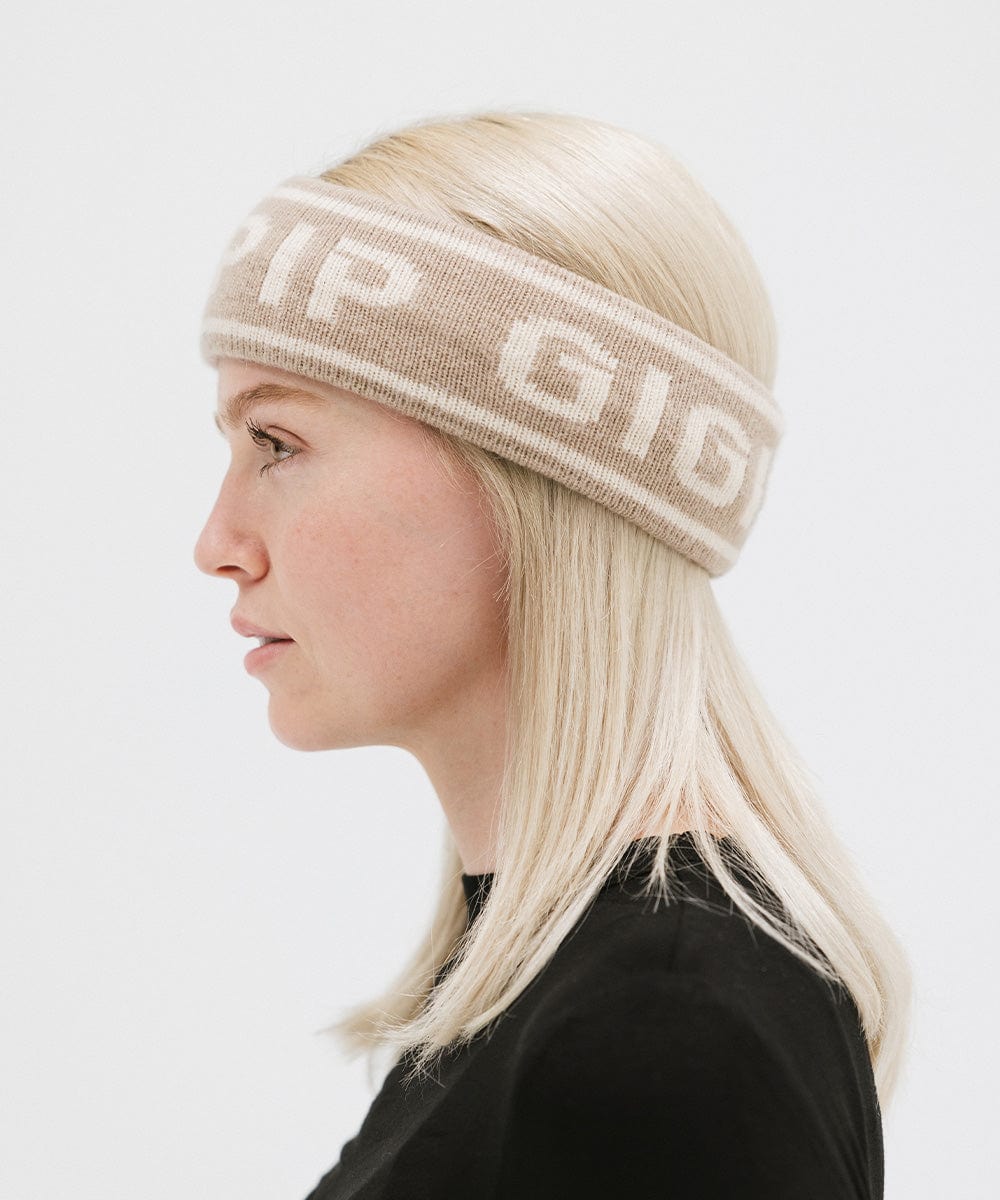 Woman wearing a taupe colored headband with 'GIGI PIP' text and a black t-shirt, facing sideways against a plain background #color_taupe
