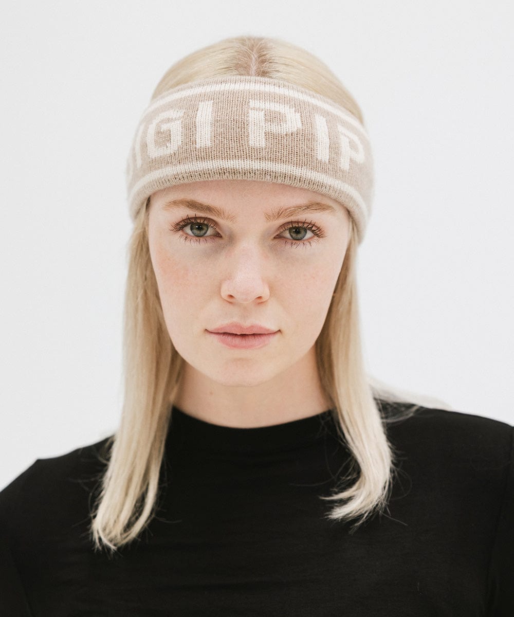 Woman wearing a taupe colored headband with 'GIGI PIP' text and a black t-shirt against a plain background #color_taupe