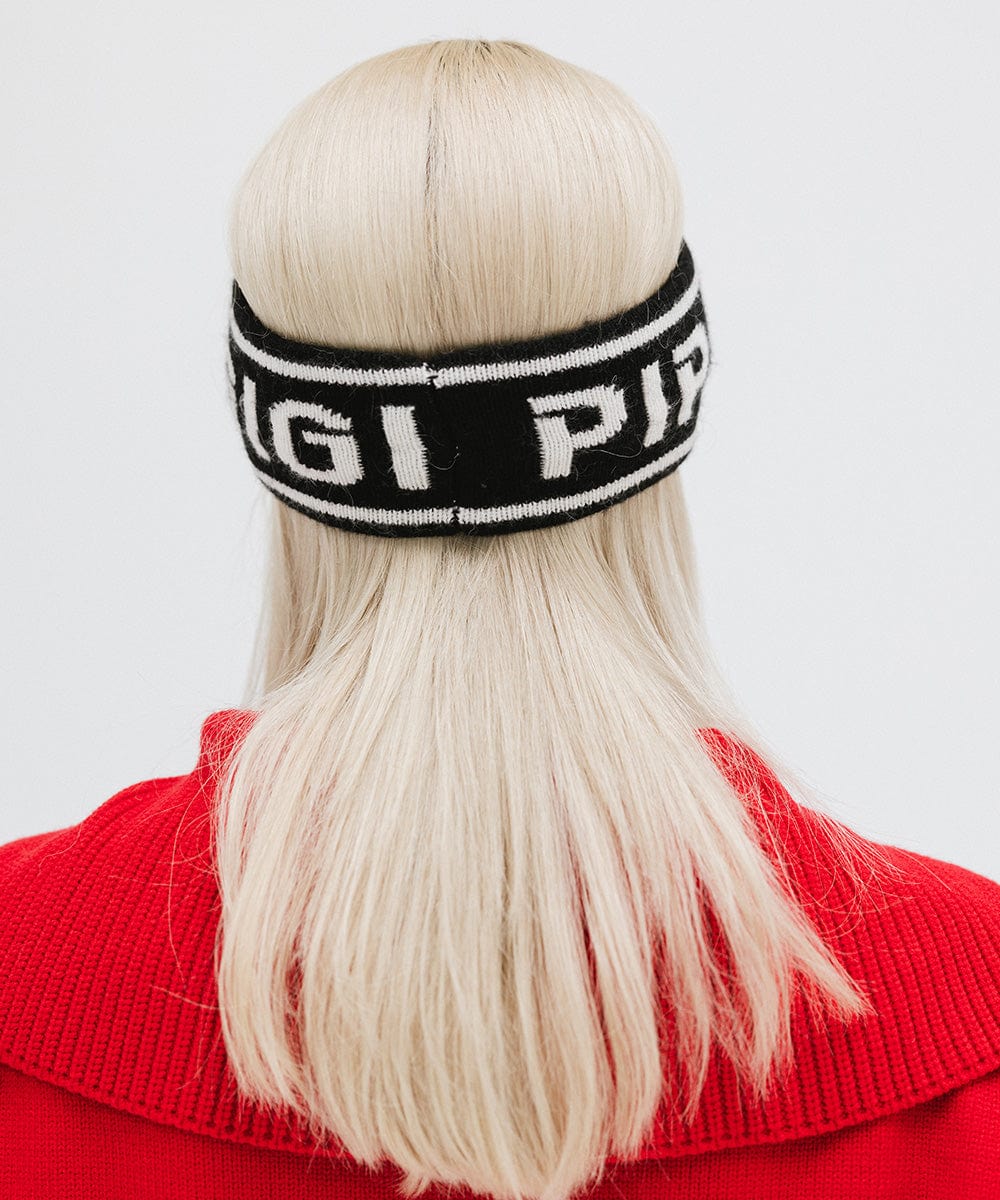 Woman wearing a black headband with 'GIGI PIP' text and a red jacket, facing behind against a plain background #color_black