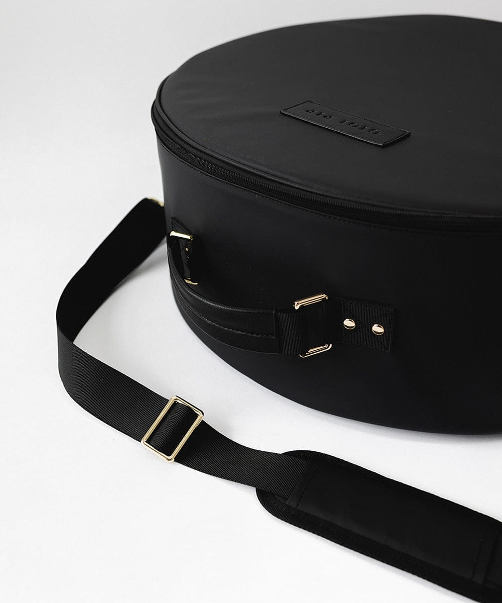A black round hat travel case with a handle against a plain background #color_black