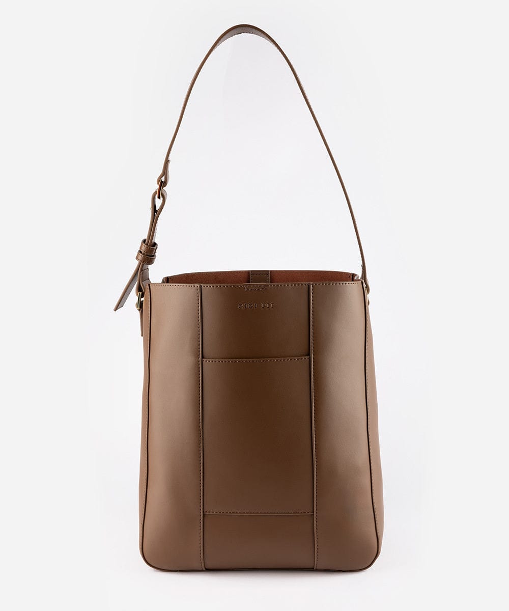 A chocolate colored Dia everyday leather tote bag with an adjustable strap and a front pocket against a plain background #color_chocolate