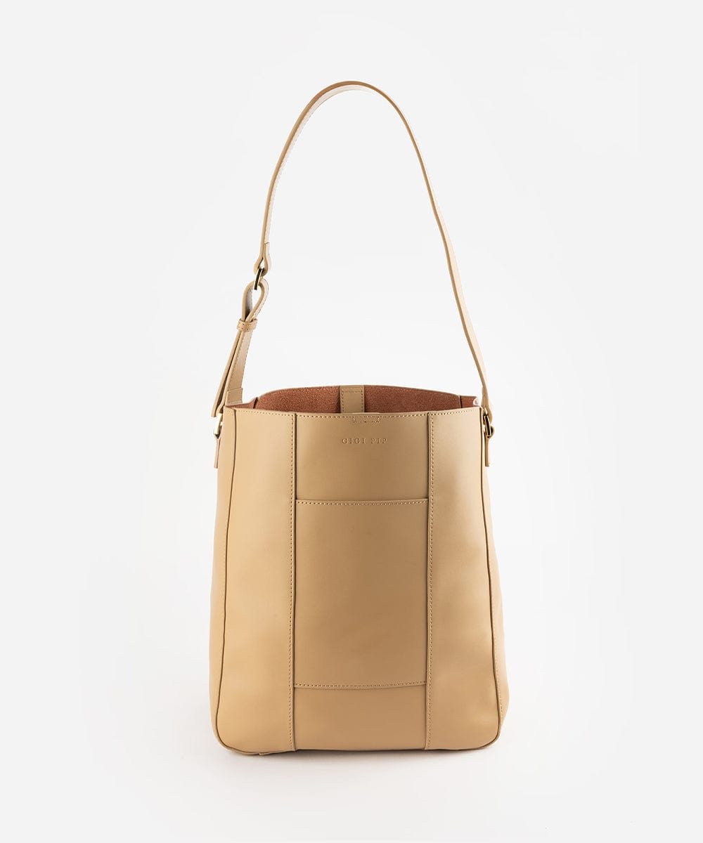 A tan Dia everyday leather tote bag with an adjustable strap and a front pocket against a plain background #color_tan