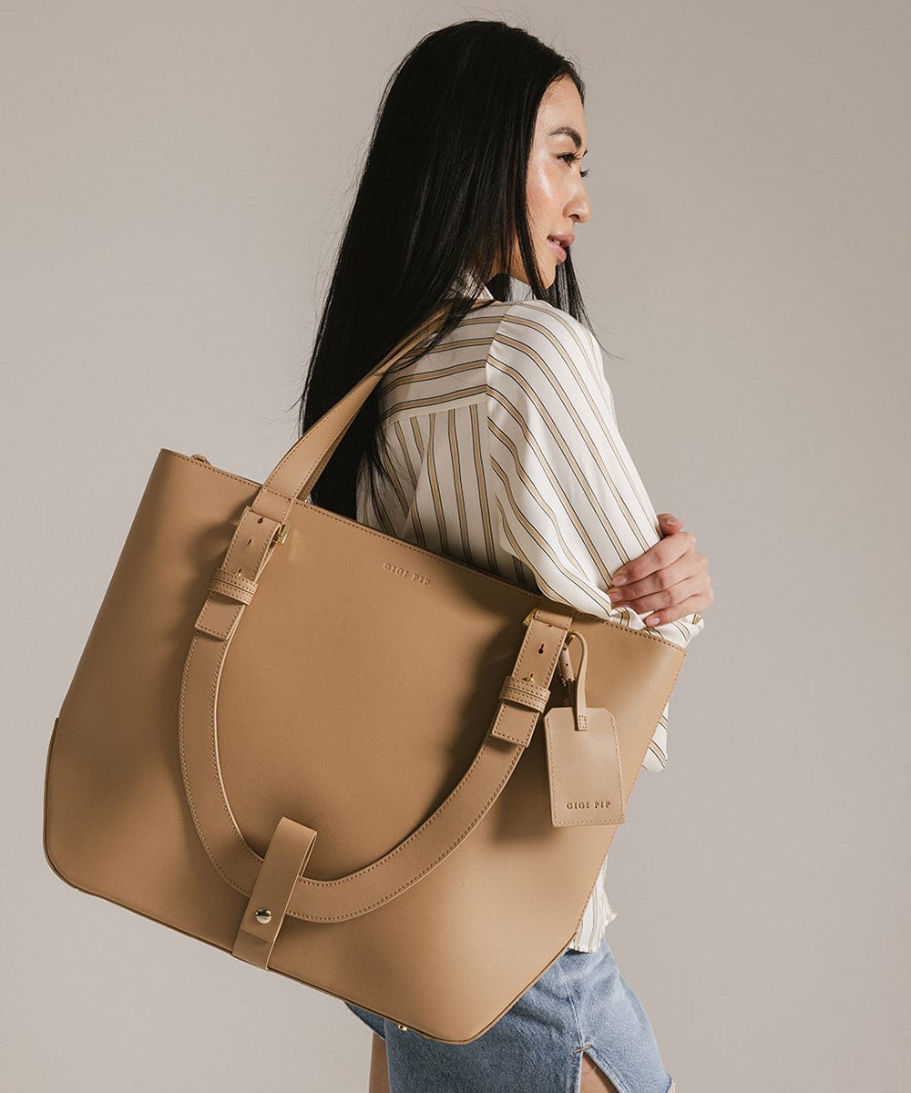 Woman carrying a beige Hayes Hat Carrying Tote bag against a plain background #color_tan