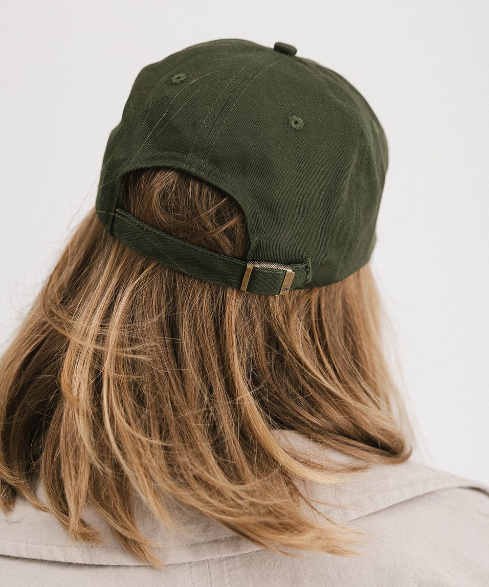 Person wearing a dark green cap against a plain background #color_dark green