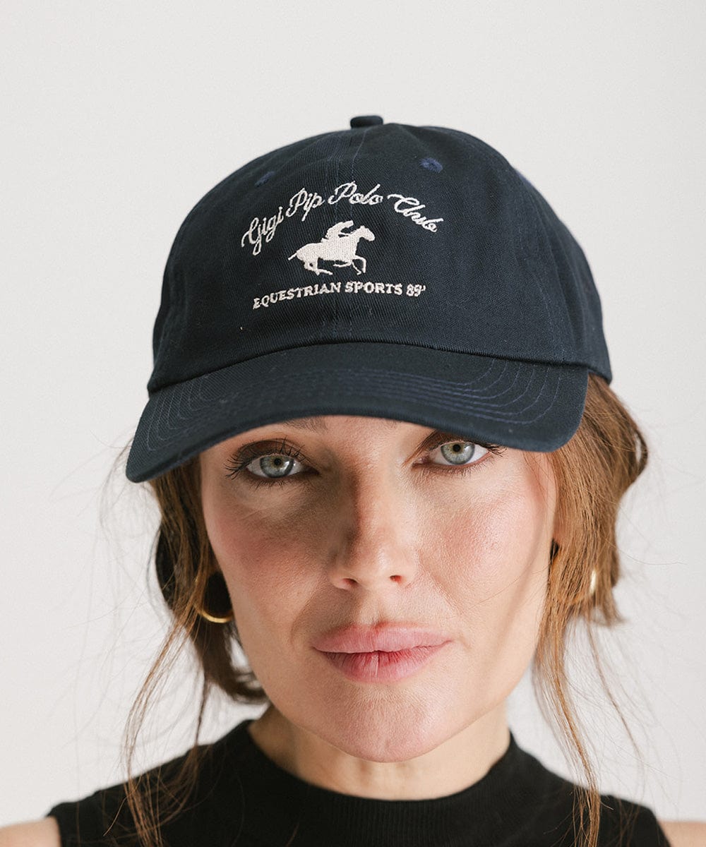 Woman wearing a navy cap with white text and horse logo against a plain background #color_navy