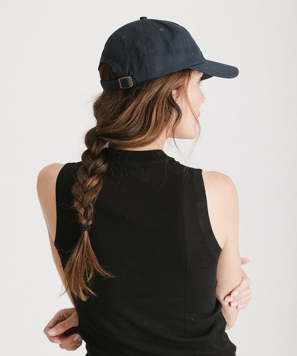 Woman wearing a navy cap and a black top against a plain background #color_navy