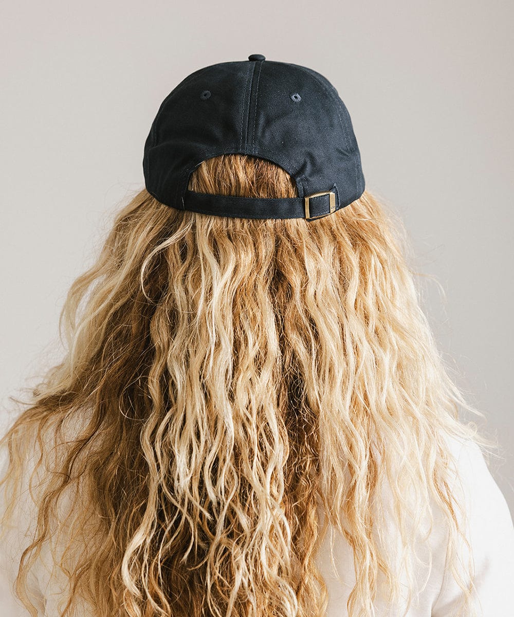 Woman with long hair wearing a navy cap against a plain background #color_navy