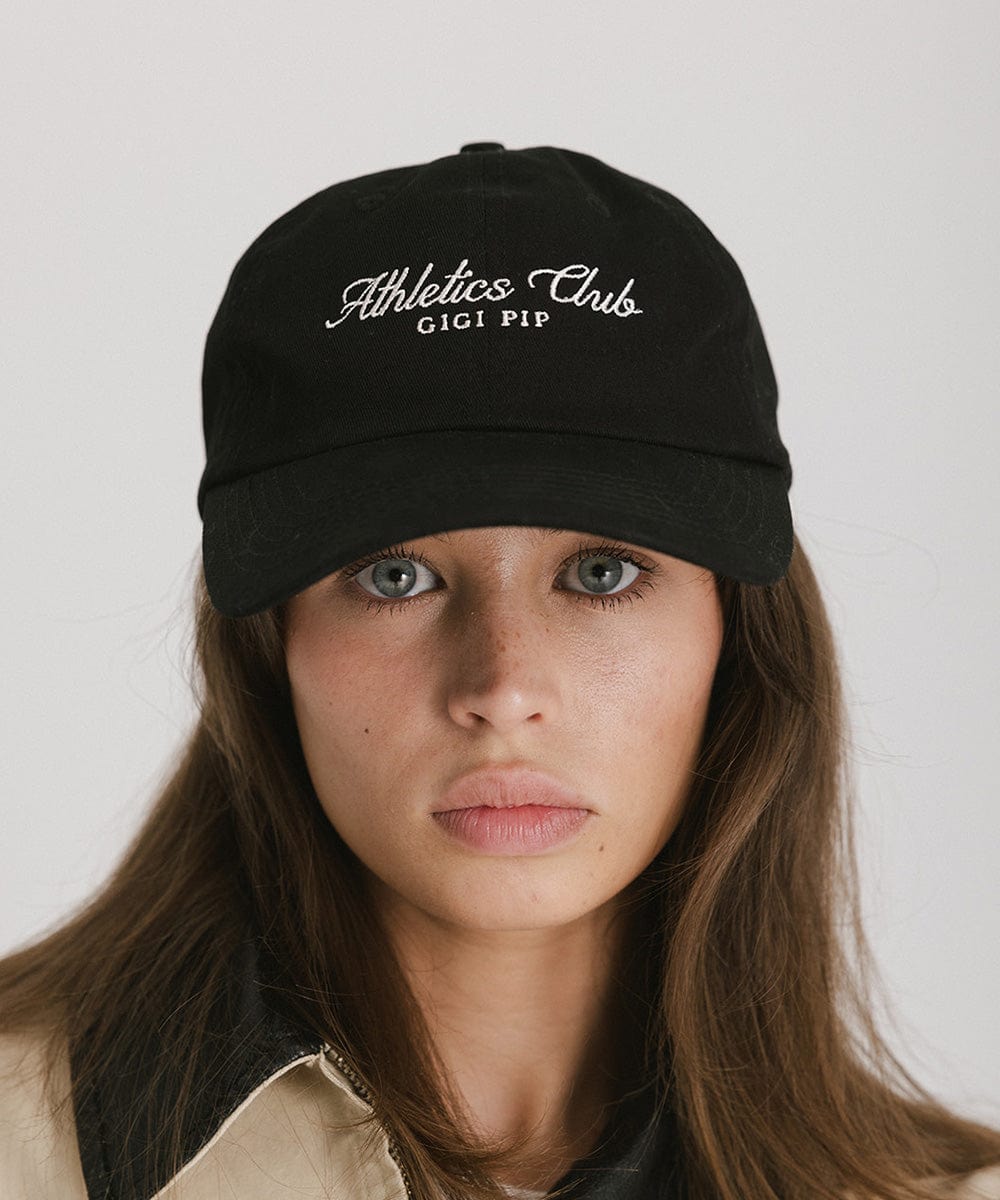 Woman wearing a black cap with white 'Athletics Club' text against a plain background #color_black