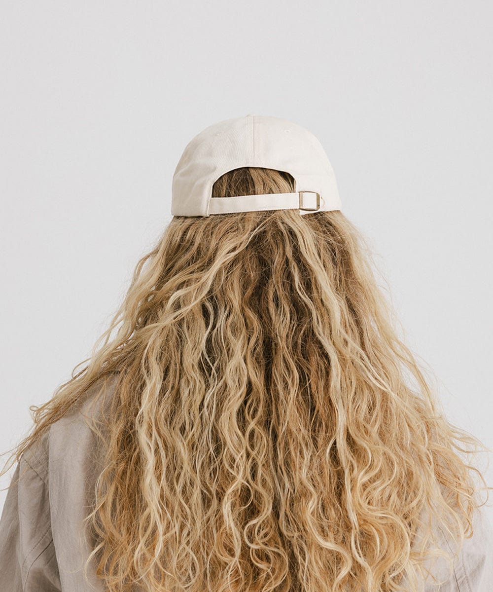 Woman with long hair wearing a cream cap against a plain background #color_cream