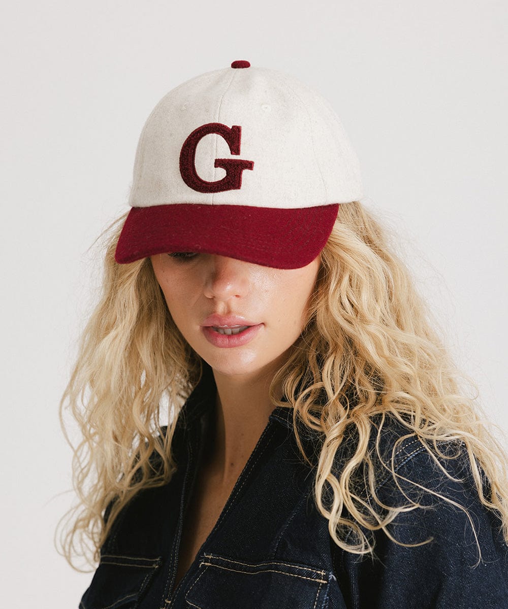 Woman wearing a white and burgundy baseball cap with the letter 'G' and a denim shirt, posing against a plain background #color_burgundy