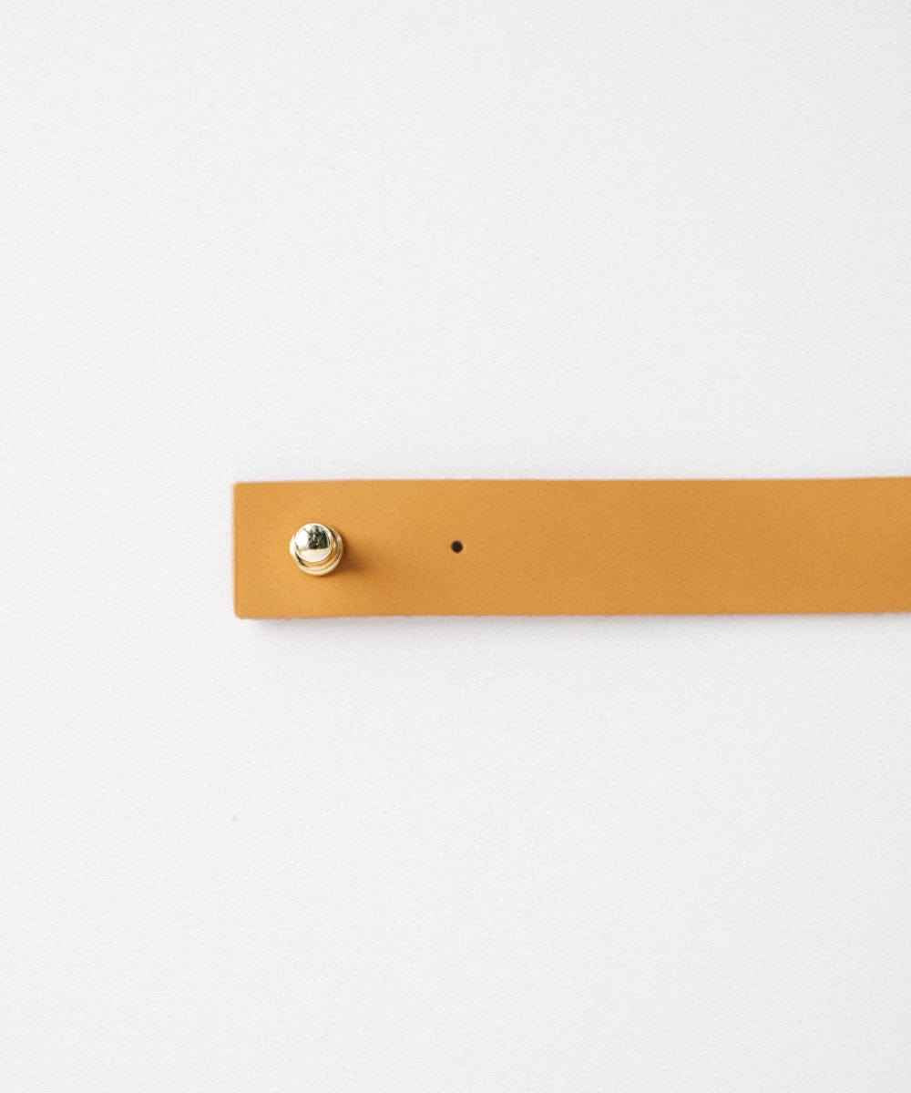 A camel colored leather band with pin on a plain background #color_camel