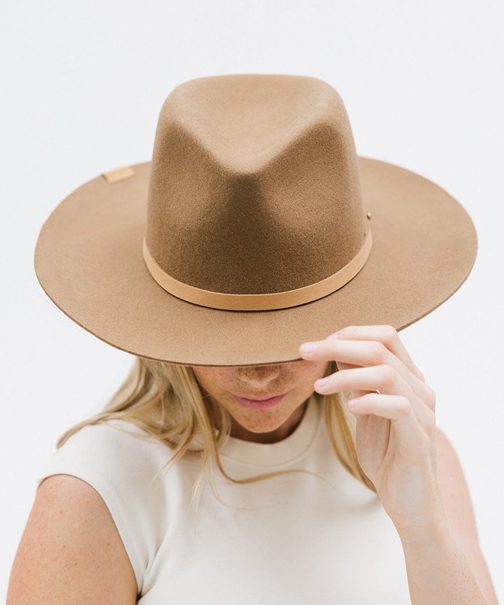 Woman wearing a beige felt hat with a thin blush colored leather hat band around the base against a plain background #color_blush