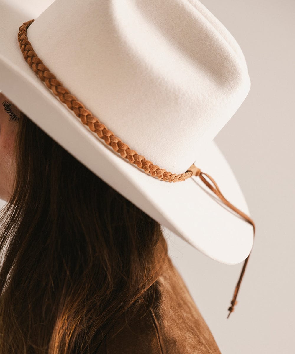 White hat with braided brown band worn by a person #color_caramel