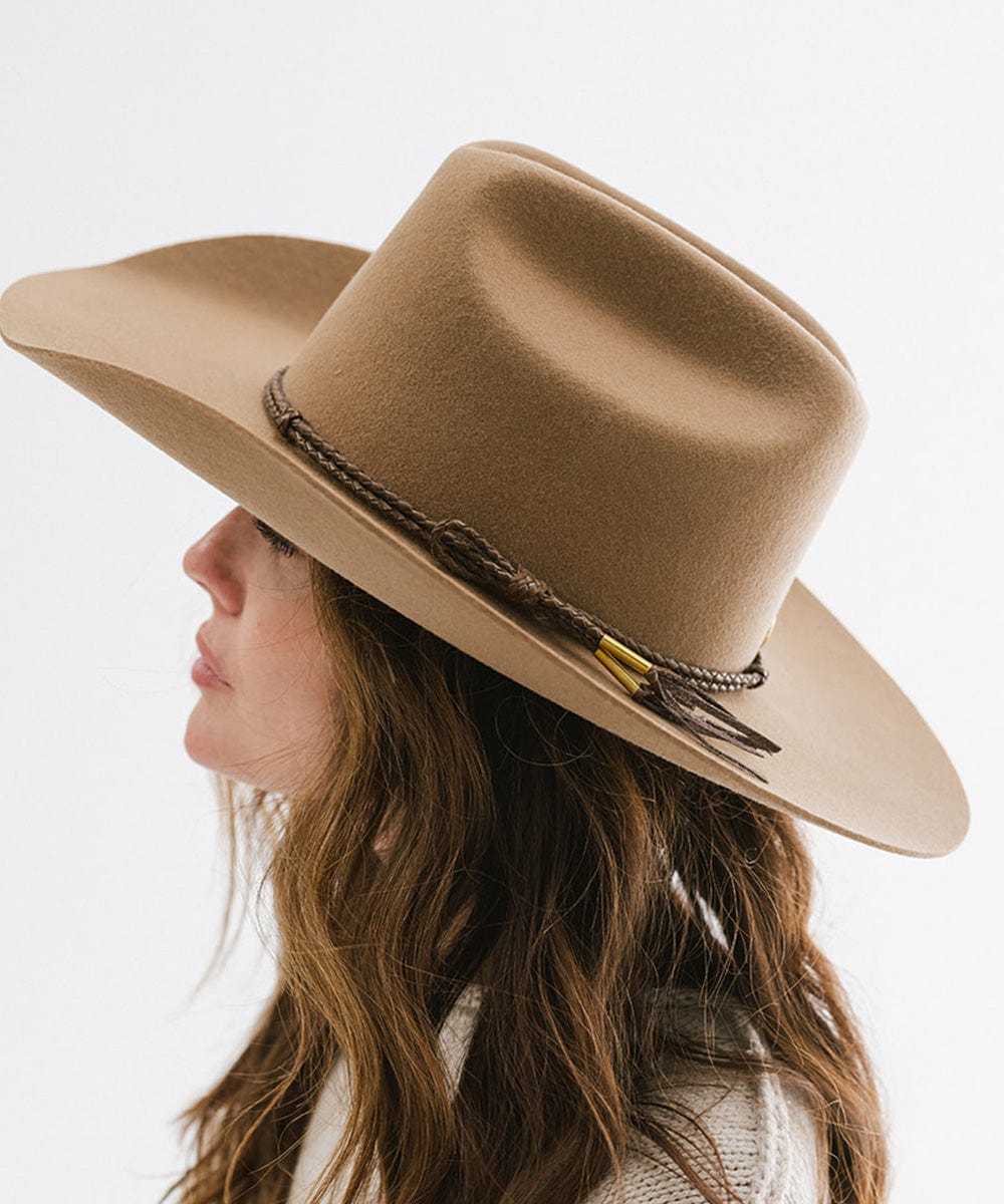 Woman wearing tan cowboy hat with a brown lasso braided hat band, facing sideways against a plain background #color_brown