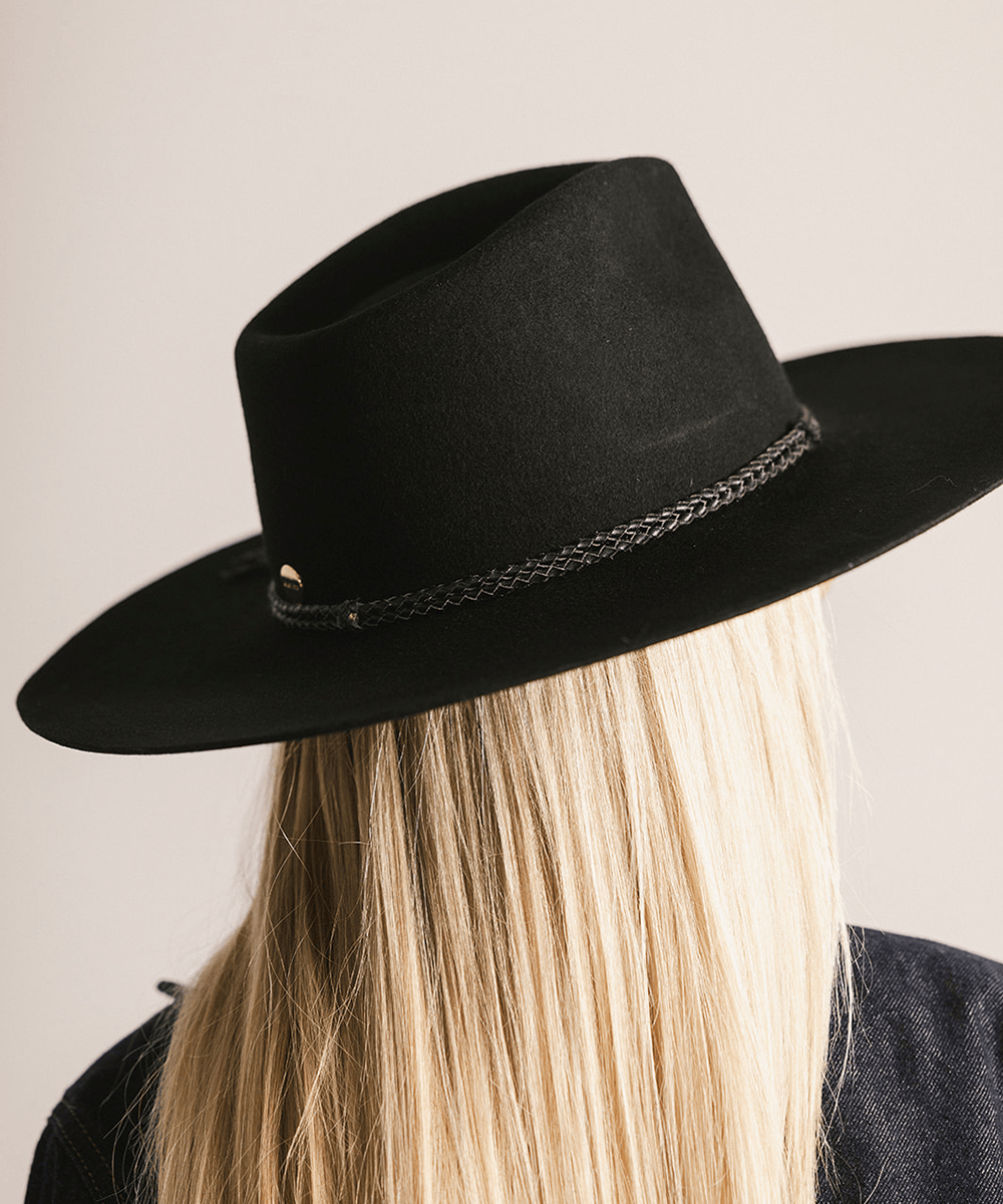 Person wearing a black hat with a chain detail on a neutral background #color_black