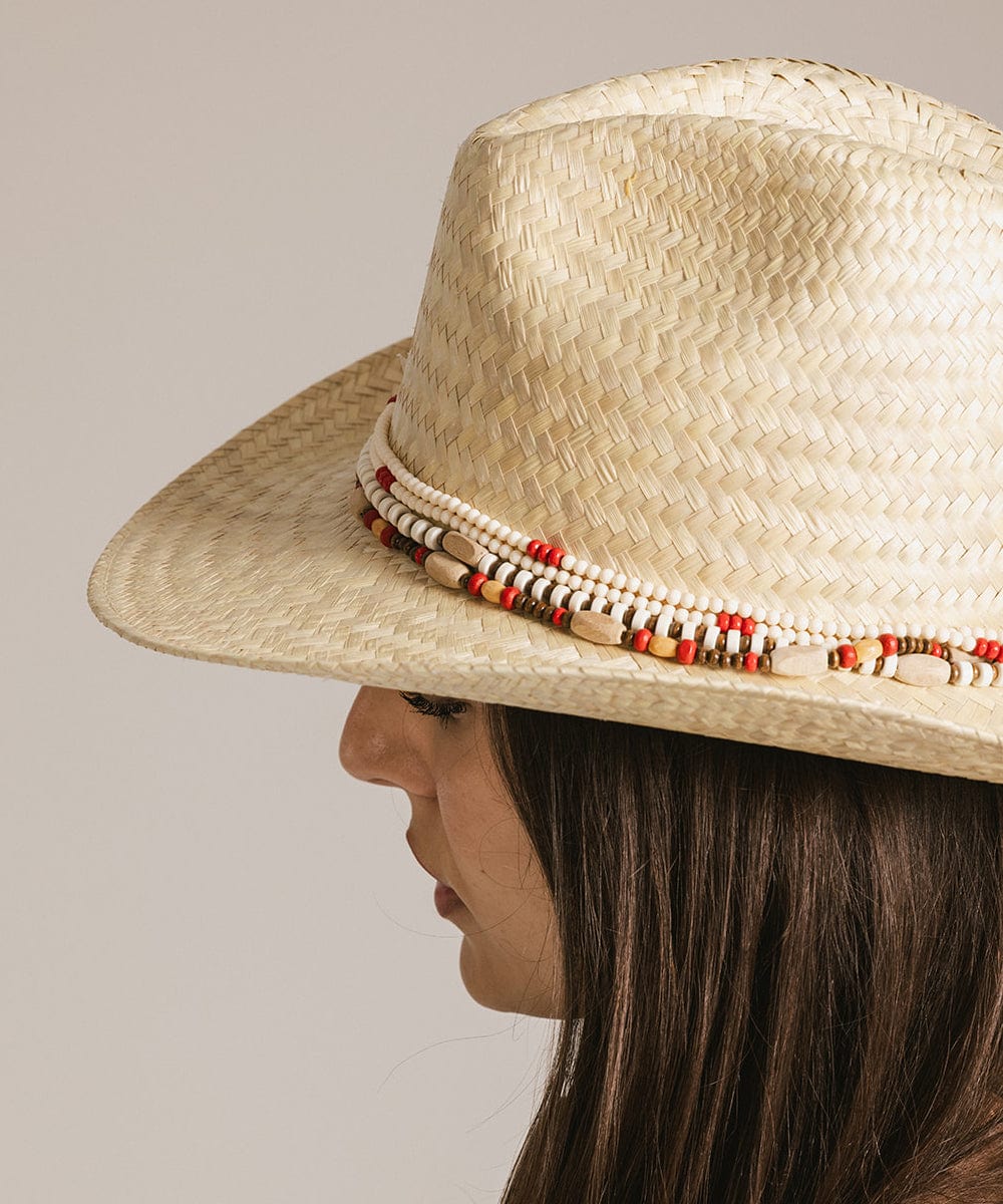 Woman wearing a beige hat with a natural colored layered beaded hat band, facing sideways against a plain background #color_natural