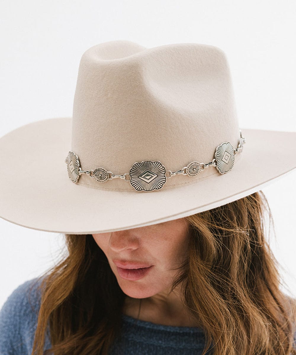 Woman wearing a cream hat with a silver western concho band against a plain background #color_silver