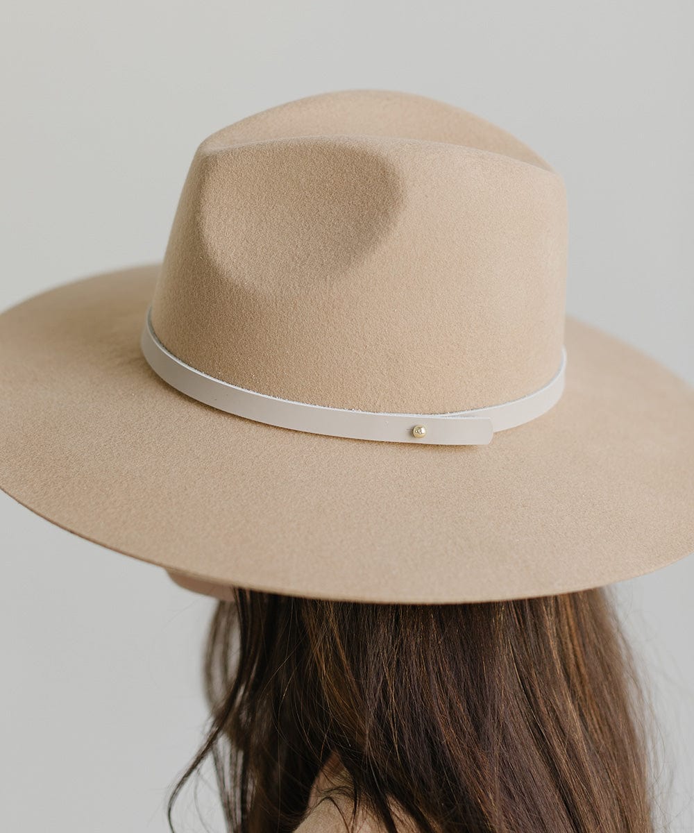Person wearing a beige felt hat with a thin stone colored leather hat band around the base against a plain background #color_stone