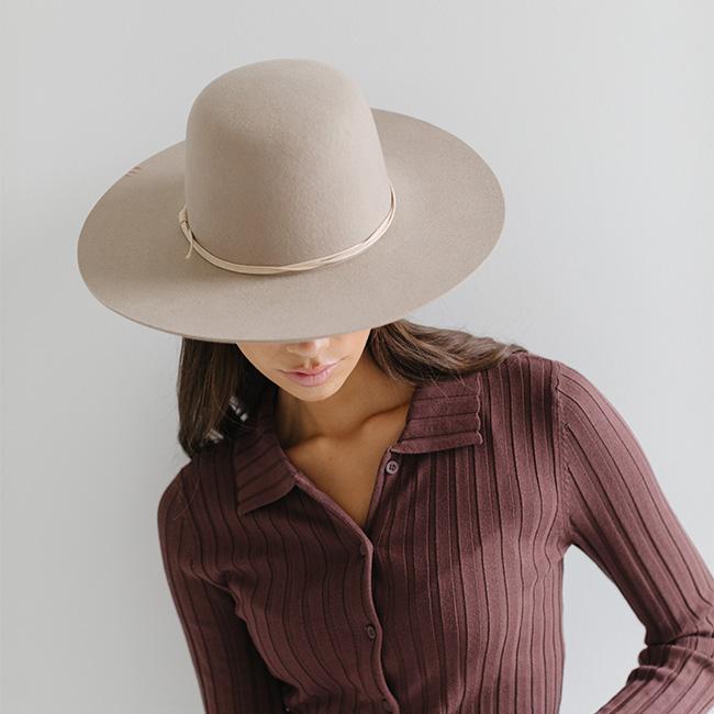 Person wearing a white cowboy hat with a cream hat band and a maroon shirt against a plain background #color_cream