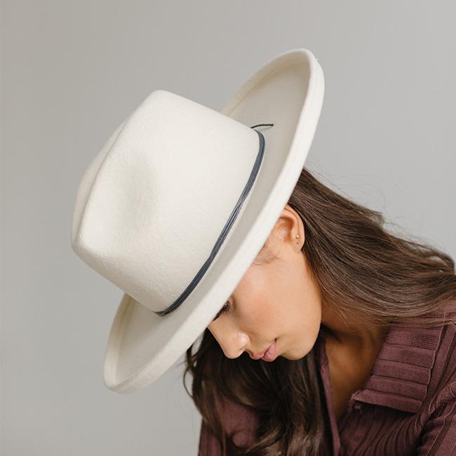 Woman wearing a white cowboy hat with a steel blue colored hat band and a maroon shirt, posing sideways against a plain background #color_steel blue