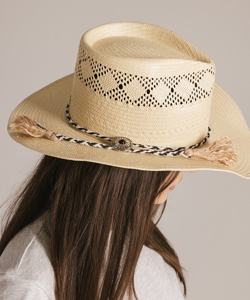 Woman wearing a beige hat with a black and white colored braided bolo tassel hat band and a grey t-shirt, facing sideways against a plain background #color_white-black
