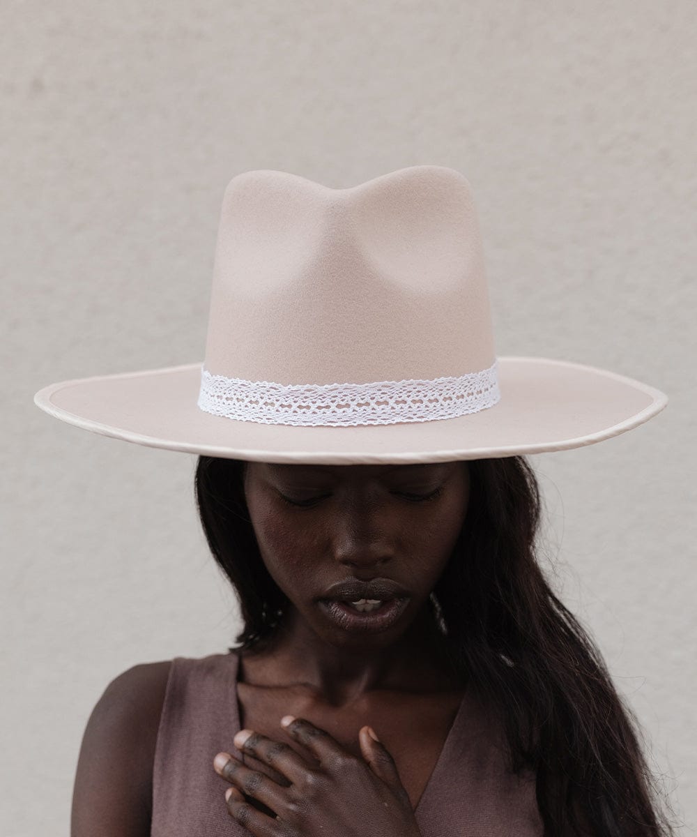 Woman wearing a cream hat with a white lace band against a plain background #color_white