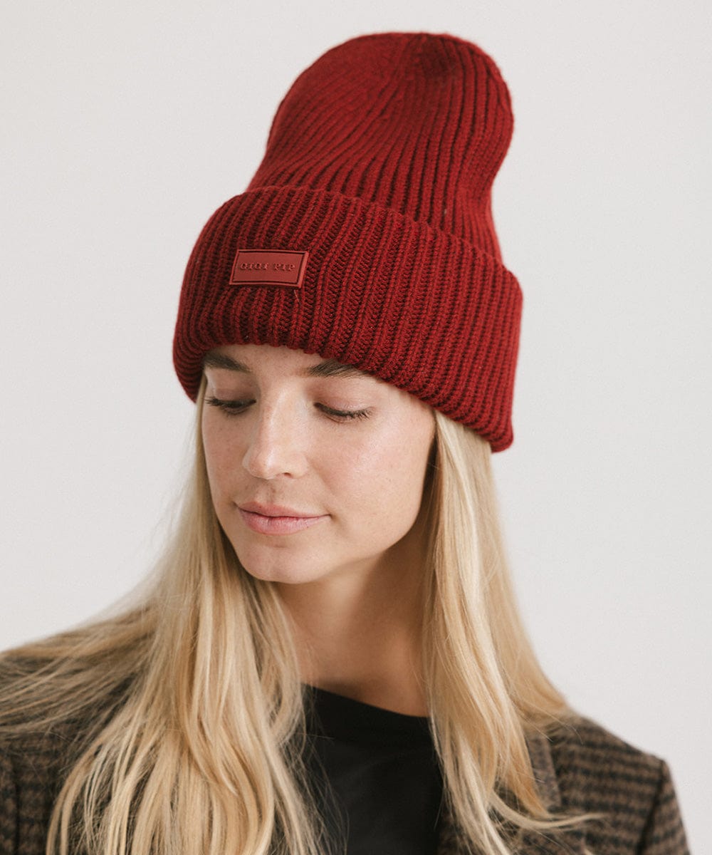 A woman wearing a burgundy chunky ribbed beanie against a plain background #color_burgundy