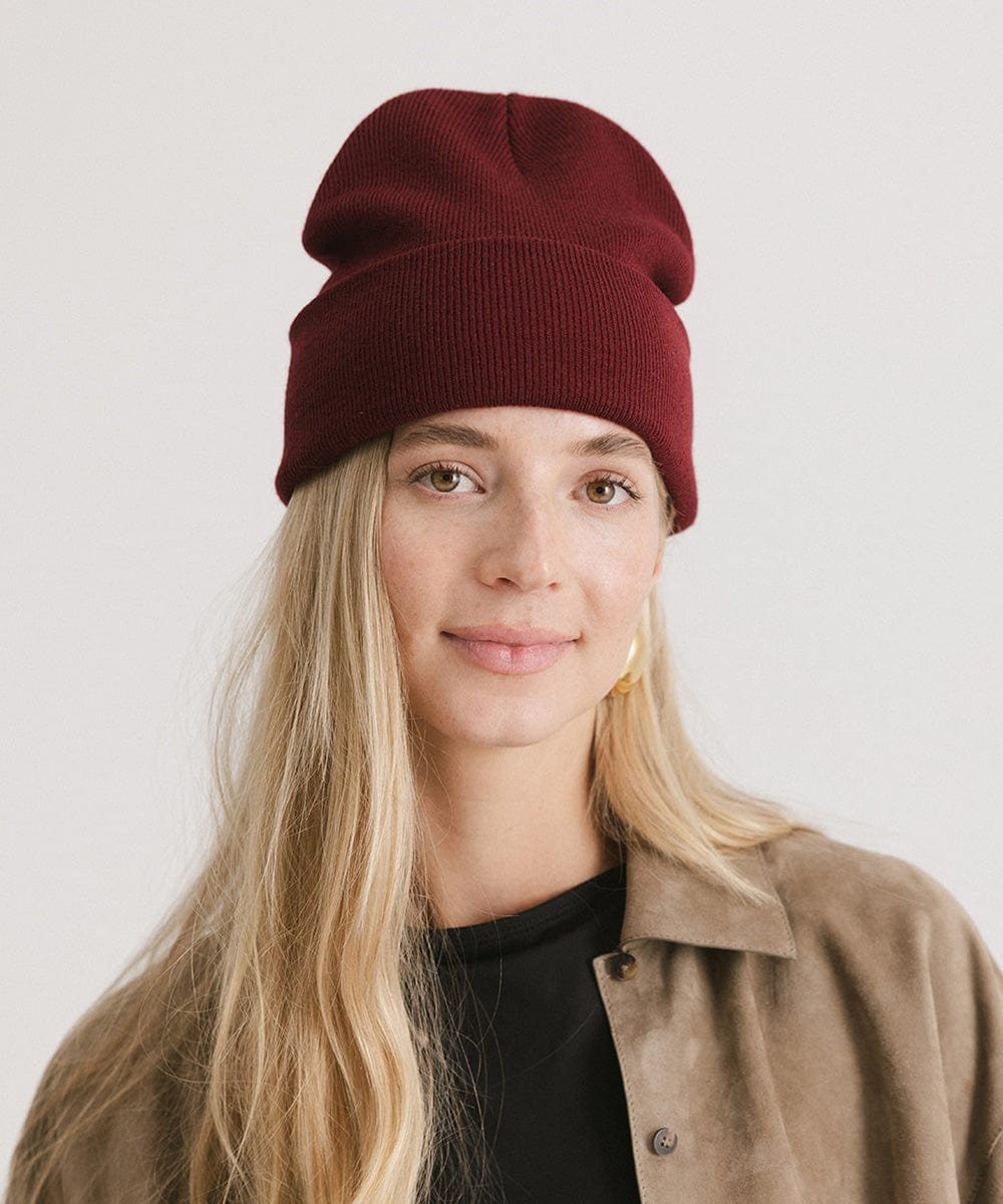 Woman wearing a burgundy beanie and a beige shirt against a plain background #color_burgundy