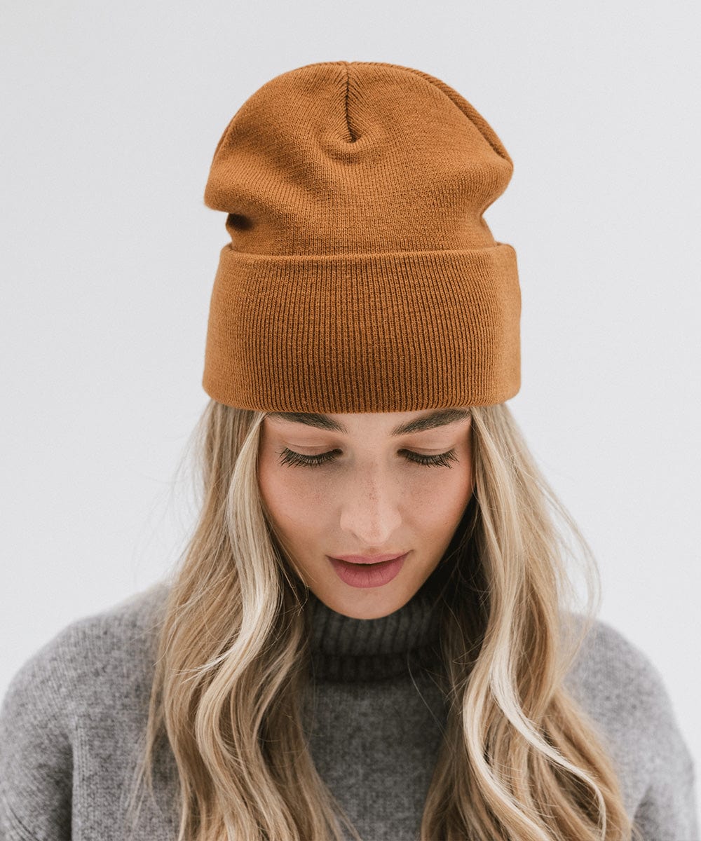 Woman wearing a cocoa colored beanie and a grey sweater against a plain background #color_cocoa