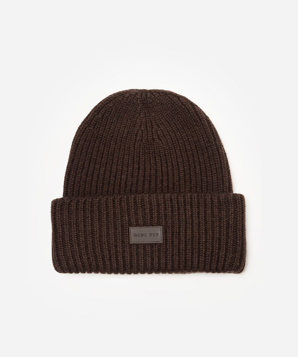 Brown knit beanie with a logo patch on a light gray background #color_dark brown