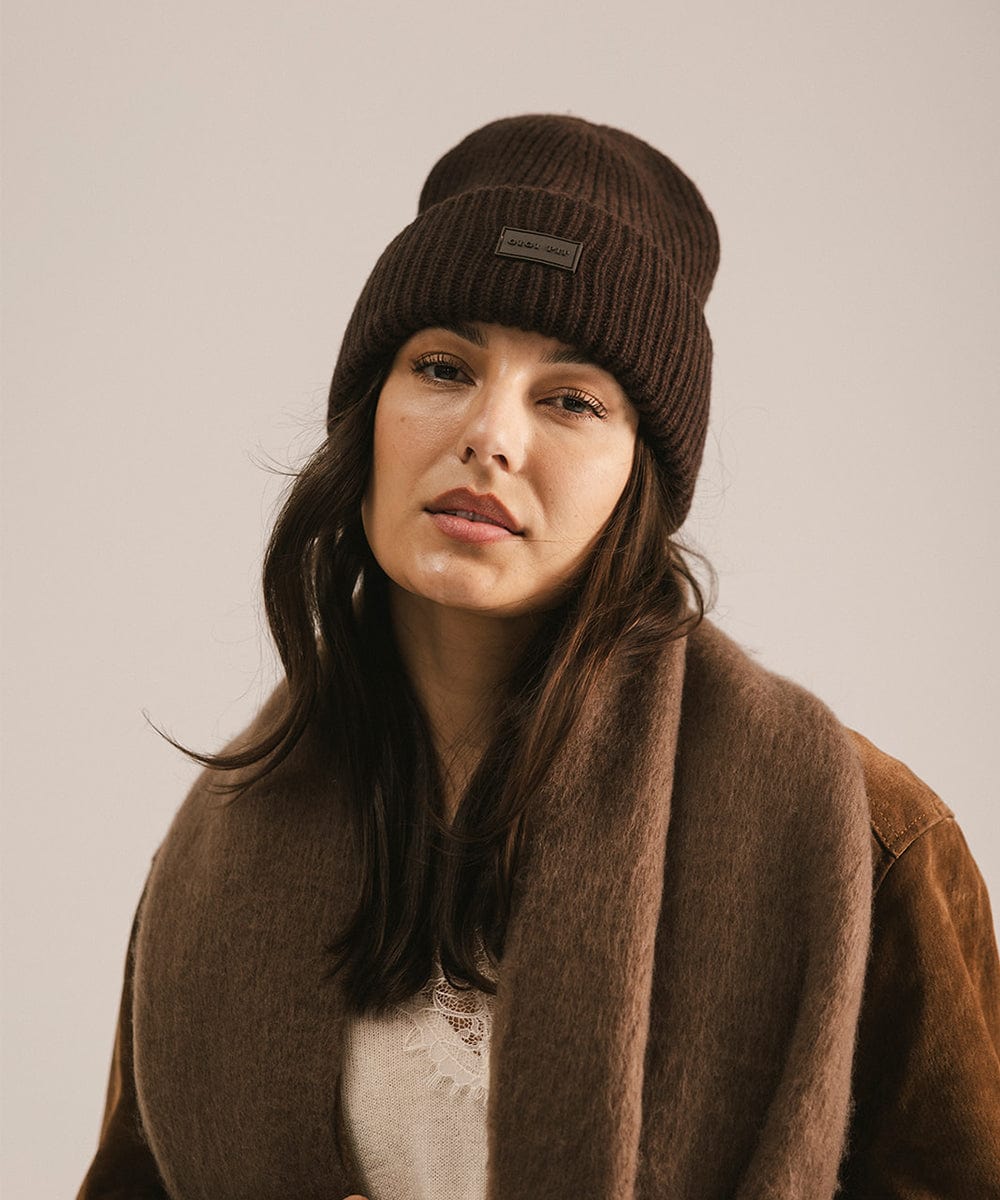 Woman wearing a dark brown beanie and scarf against a plain background #color_dark brown
