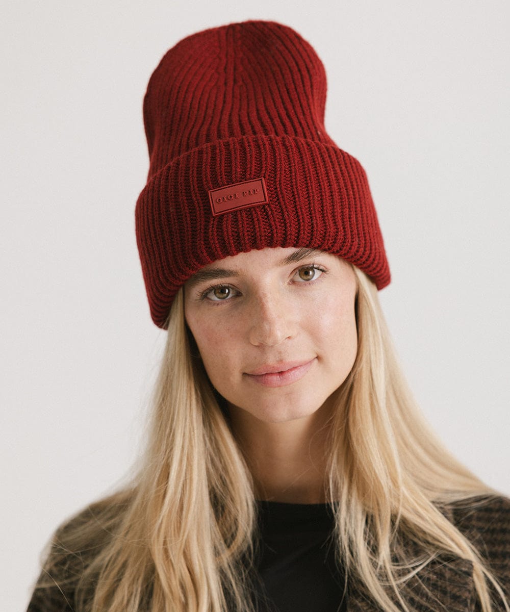 A woman wearing a burgundy chunky ribbed beanie against a plain background #color_burgundy