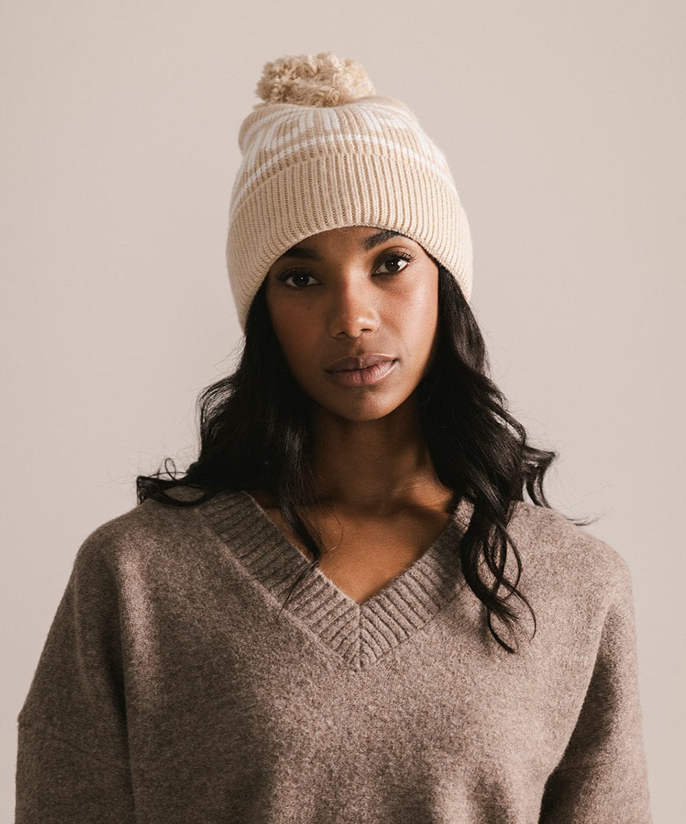 Woman wearing a beige knit beanie and sweater against a plain background #color_taupe
