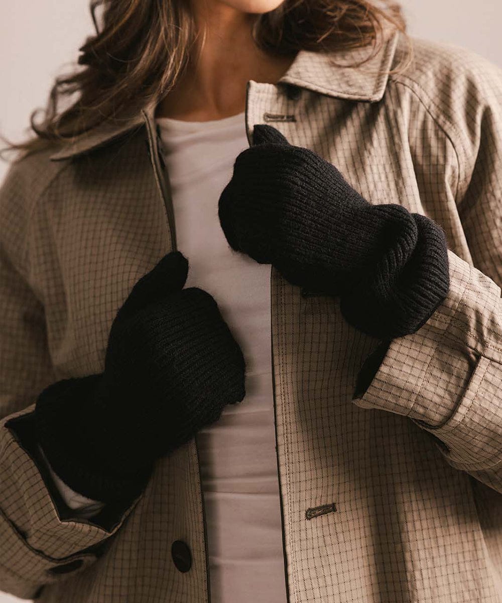 Person wearing a beige checkered coat and black gloves with a neutral background #color_black