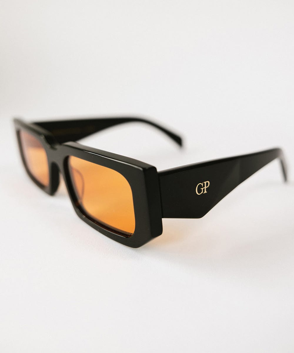 Close up image of sunglasses with black frame and orange lenses on a white background #color_black