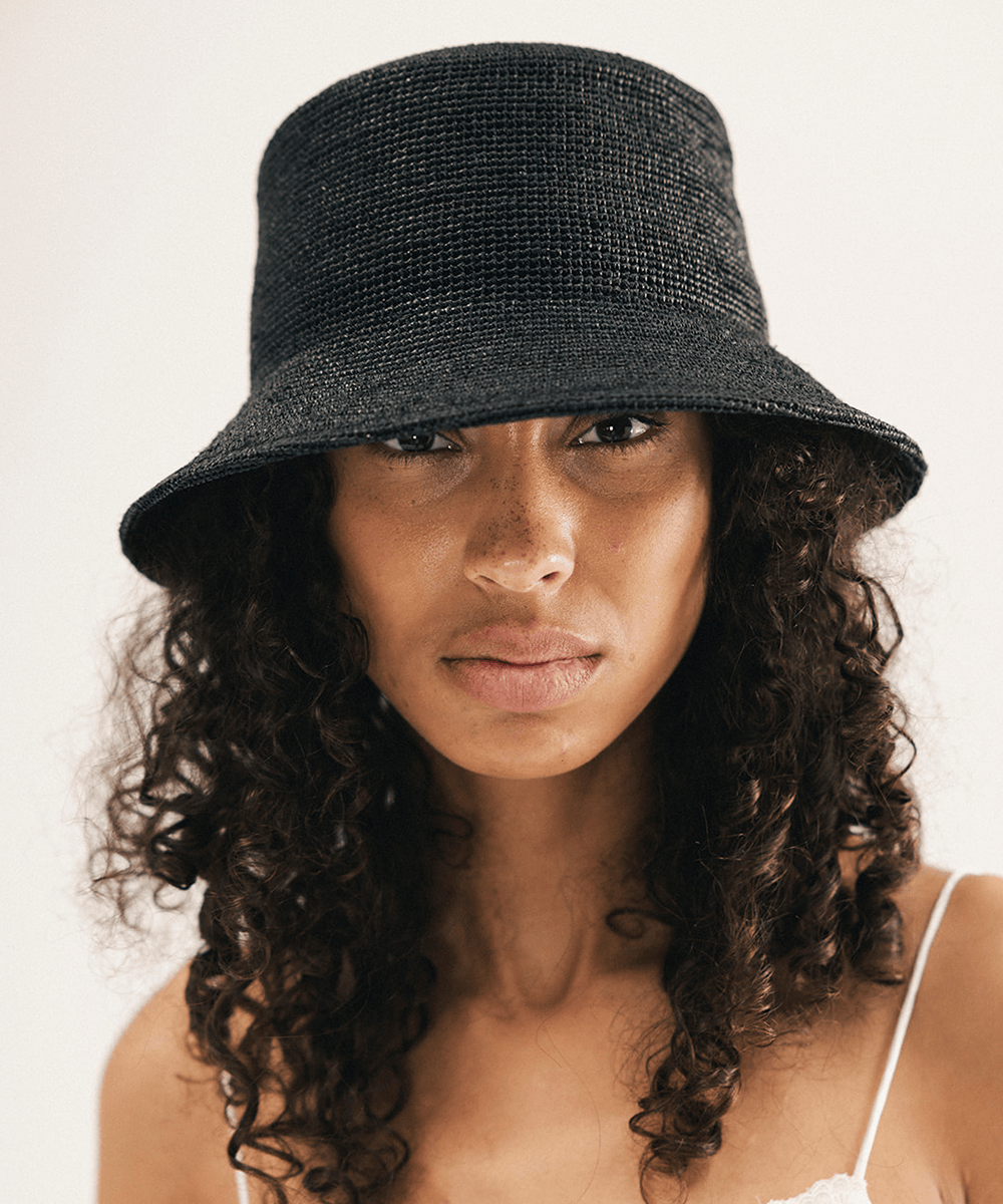 Woman wearing a black bucket hat against a white background #color_black