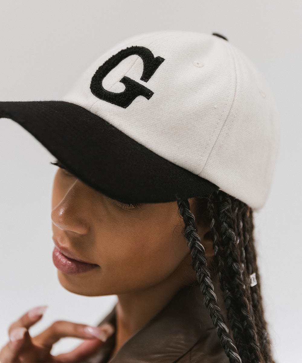 Woman wearing a cream and black baseball cap with the letter 'G' against a plain background #color_cream-black