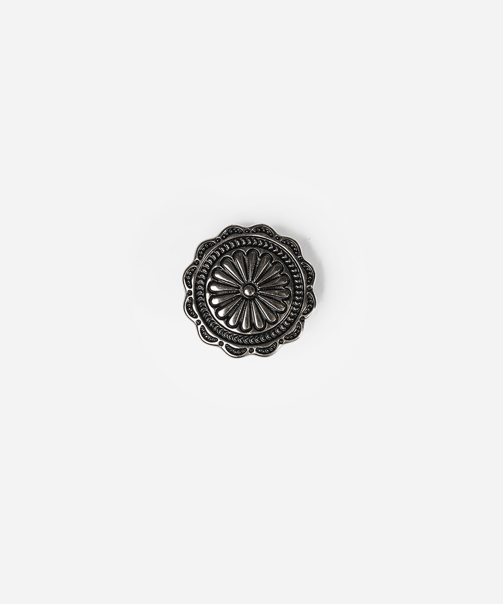 A single round, scalloped metal button with an embossed floral or sunburst pattern, shown on a plain light gray background #color_silver