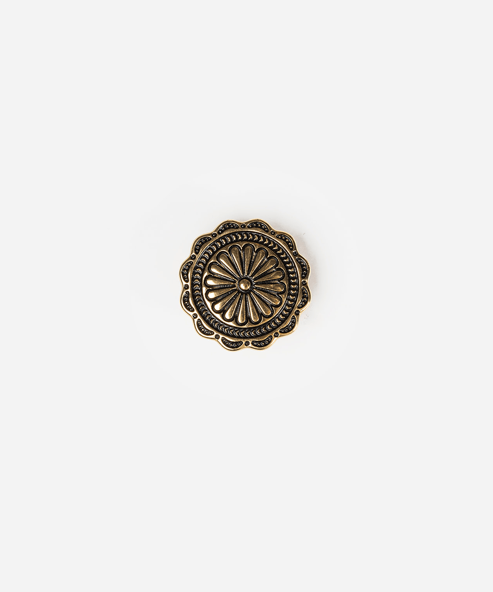 An antique bronze decorative button with a floral sunburst pattern and scalloped edges, centered on a plain light gray background #color_gold