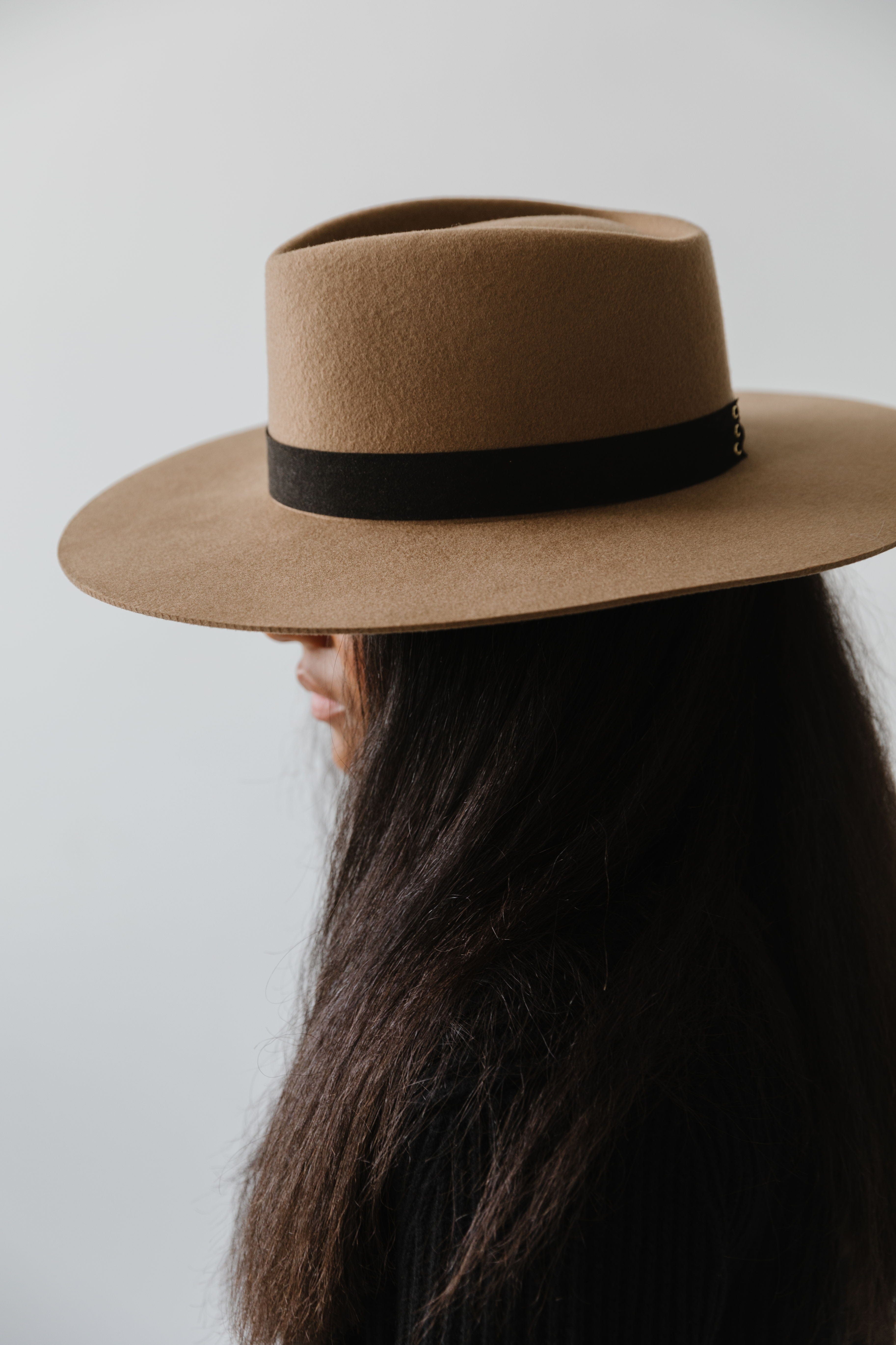 Woman wearing a brown hat with a black corset band facing sideways against a plain background #color_black