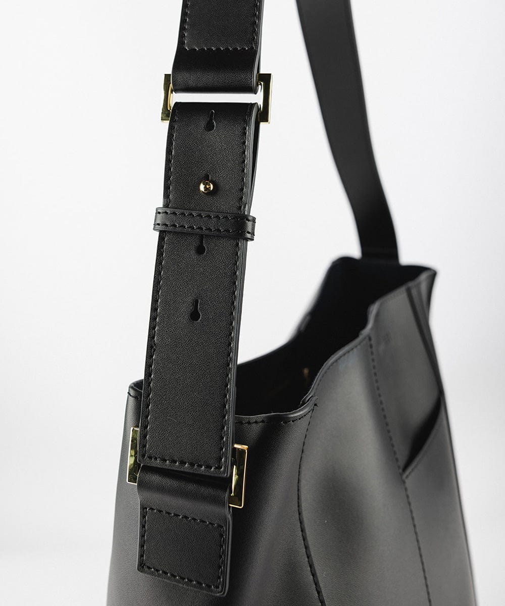 Close up image of the side of a black Dia Everyday Leather Tote Bag against a plain background #color_black