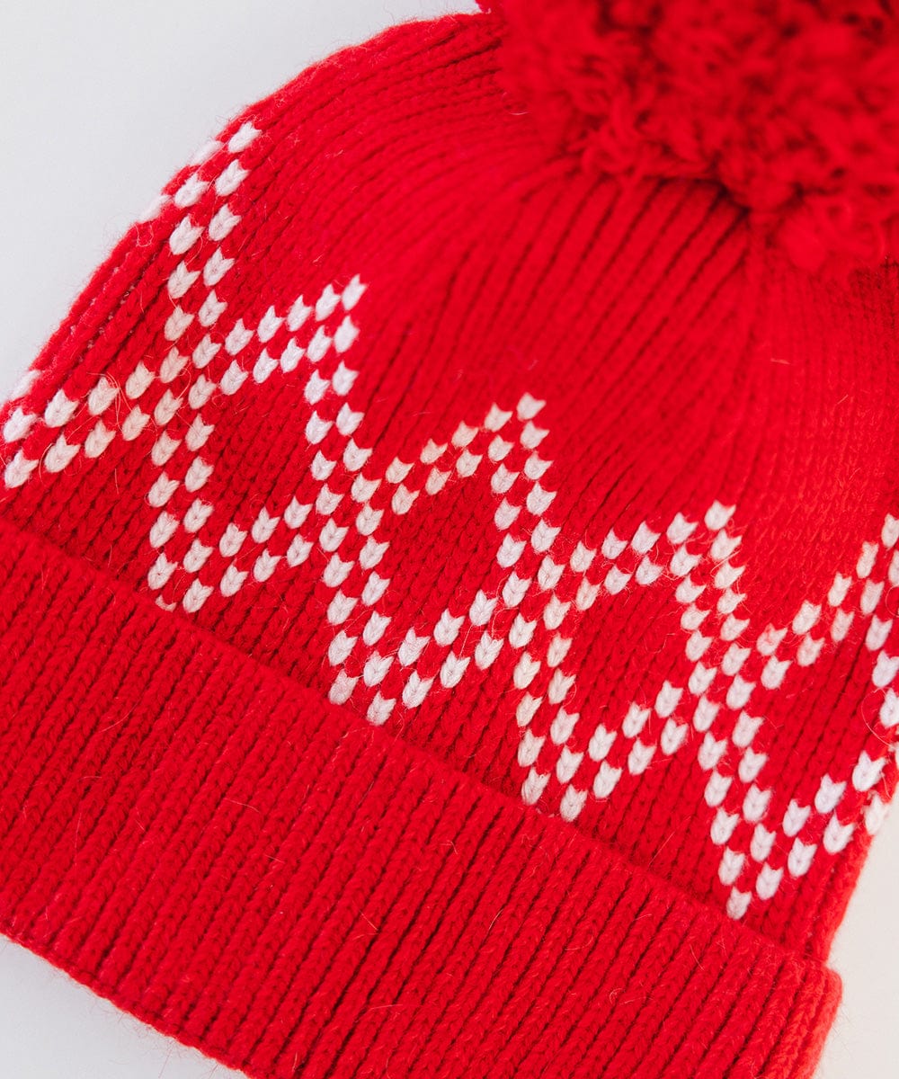 Close up image of a ruby red colored knit beanie with a pom-pom on a white background #color_ruby red