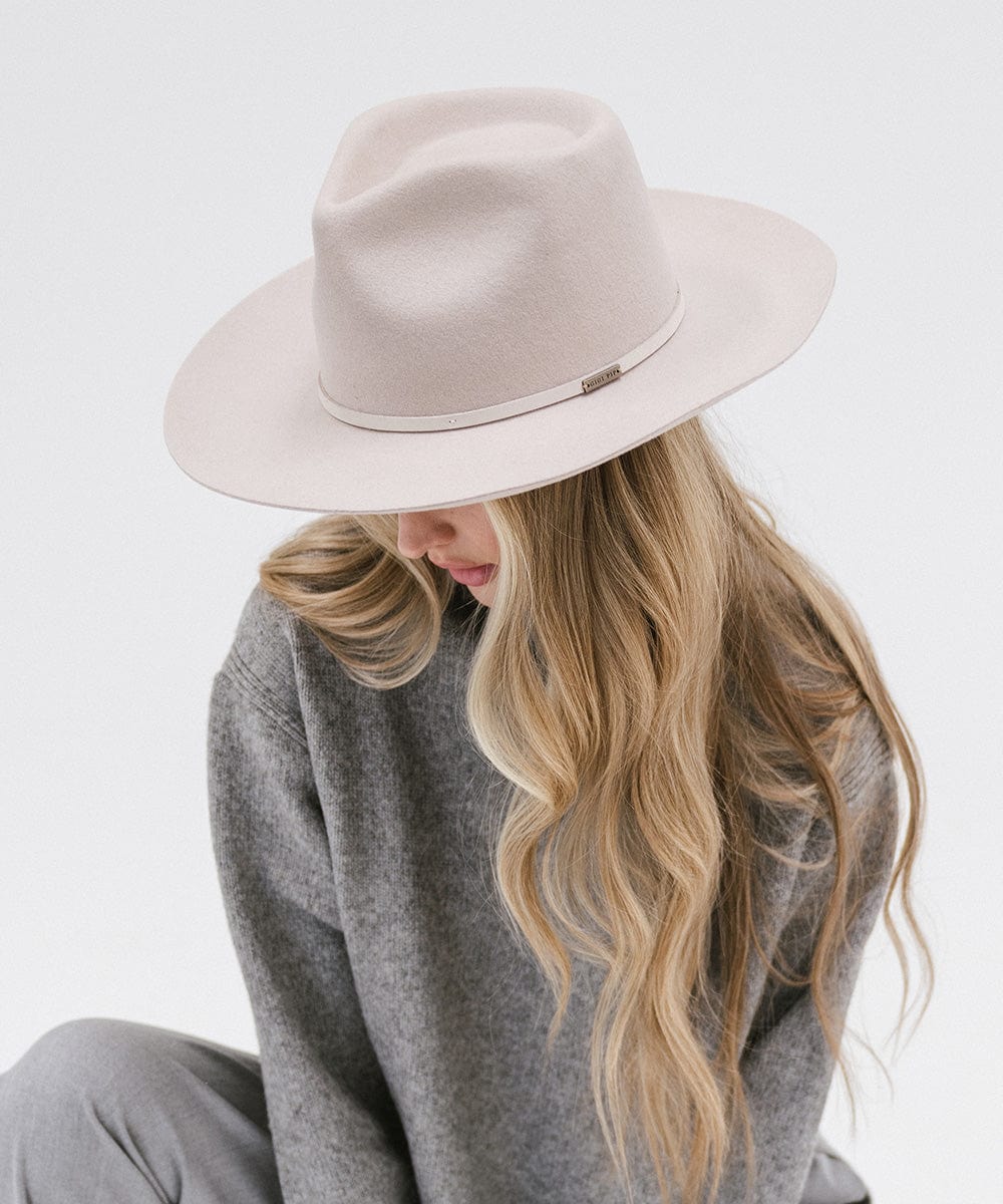 Woman with long hair wearing an ivory colored Rowan Wide Brim Fedora Hat and a grey sweatshirt against a plain background #color_ivory