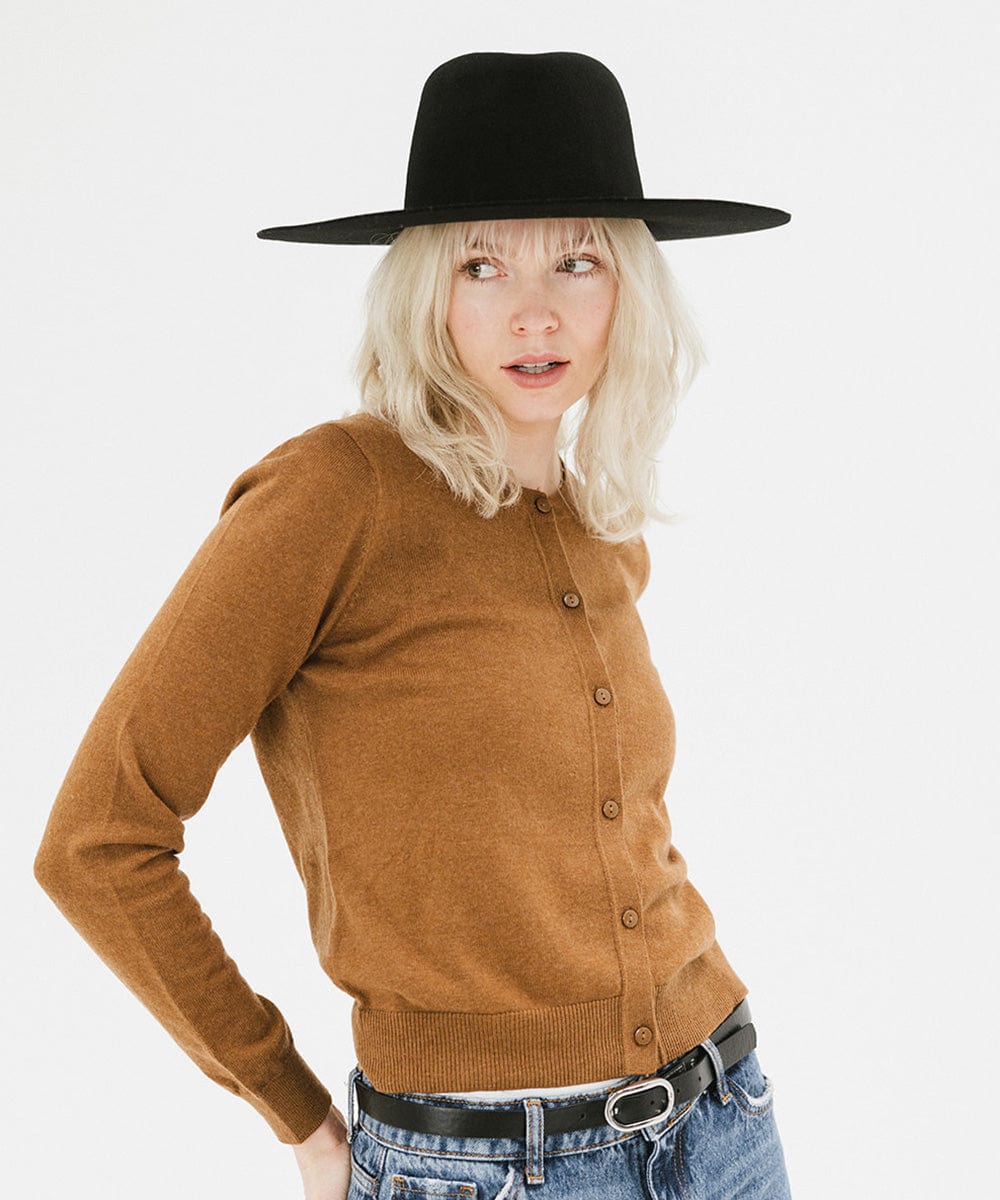 Woman wearing a black wide brim felt hat with a triangle crown and a brown shirt against a white background #color_black