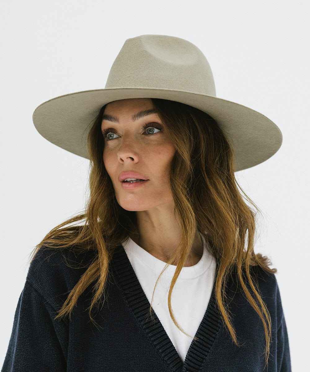 Woman wearing a sage colored wide brim fedora hat and a blue sweater against a plain background #color_sage
