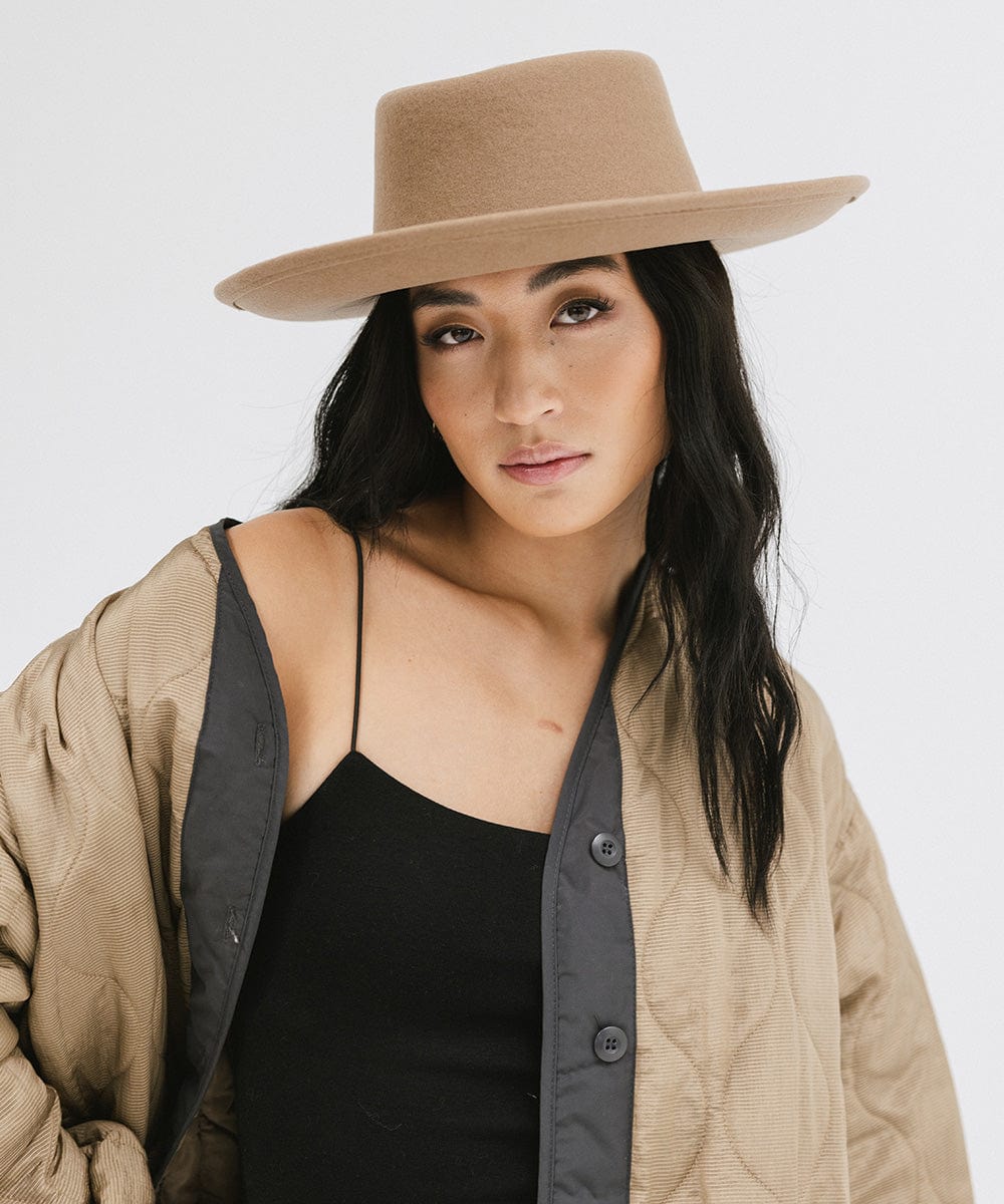 Woman wearing a brown gambler hat and a black top with a brown jacket against a plain background #color_brown