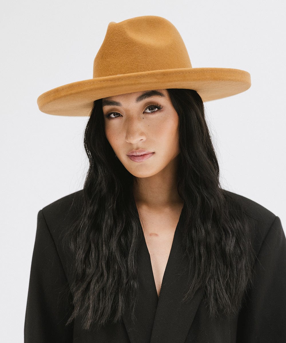 Woman wearing a cinnamon colored pencil brim felt fedora hat and a black blazer against a white background #color_cinnamon