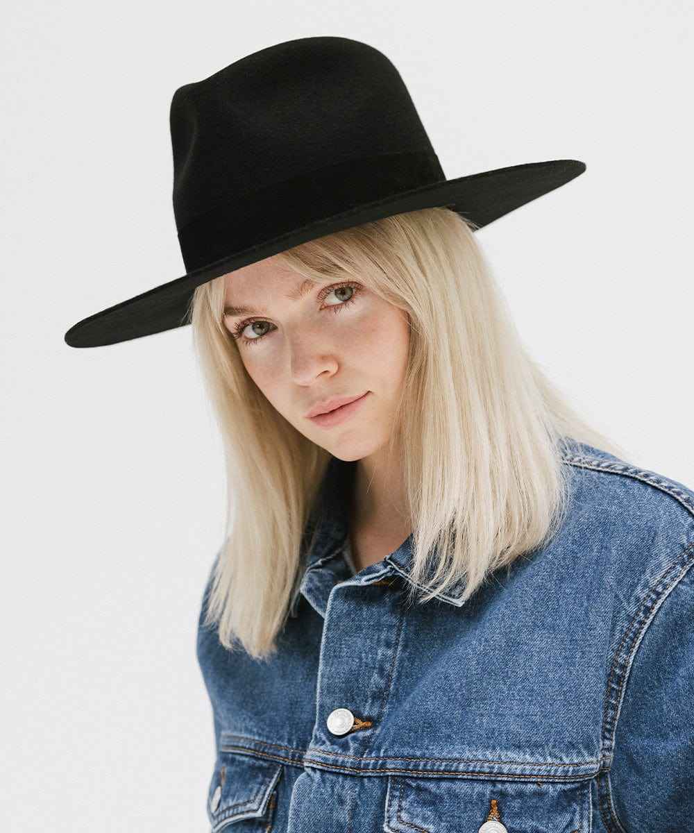 Woman wearing a black fedora hat with a band and denim jacket on a white background #color_black